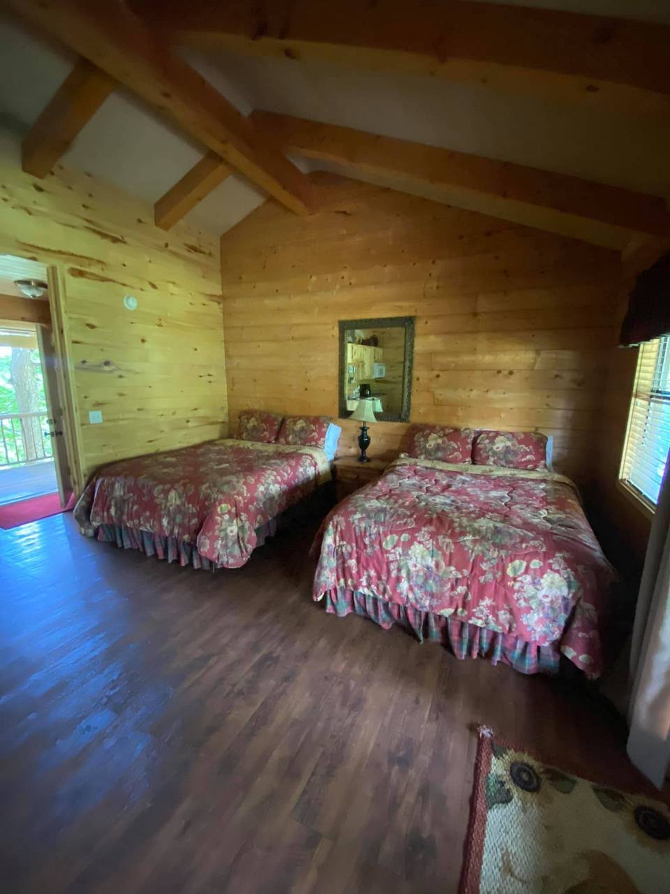 Lodge bedroom with two beds, a nightstand lamp, and a wall mirror at Sabinal River Lodge