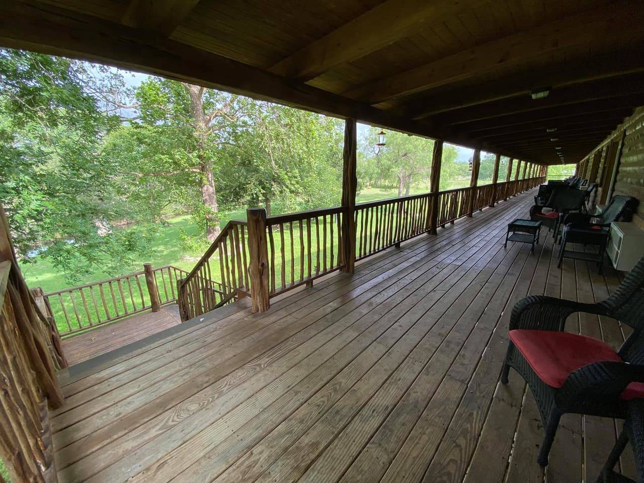 Wraparound porch at Sabinal River Lodge with wicker seating and river-view railing