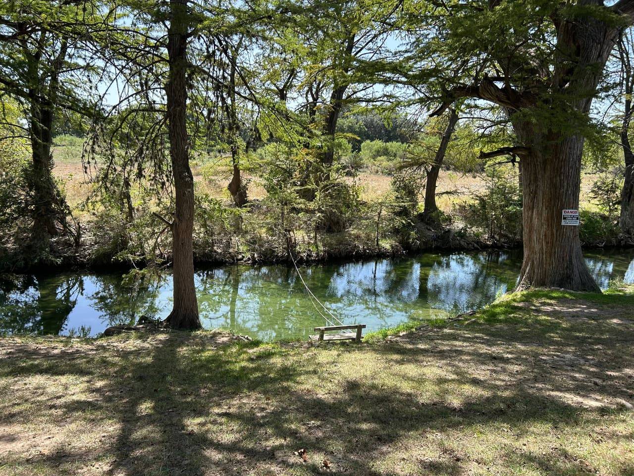 Direct Sabinal River access at Sabinal River Lodge, a shaded swimming hole with a rope swing beneath cypress trees in Utopia, Texas