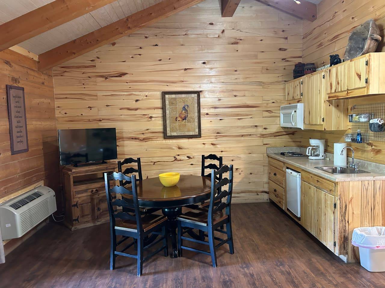 Furnished kitchenette and dining area at Sabinal River Lodge with a round table, chairs, TV, and small appliances
