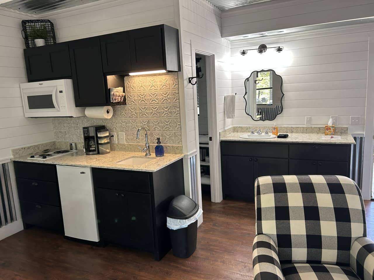 Lodge kitchenette and bathroom vanity at Sabinal River Lodge with black cabinets and marble-look counters